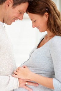 Portrait of affectionate young man holding his pregnant wife's belly